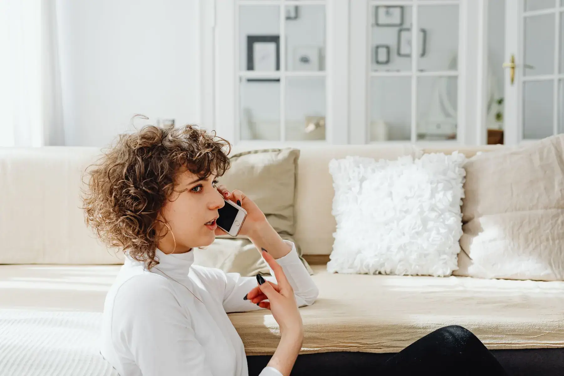 Woman talking on a phone on a living room sofa