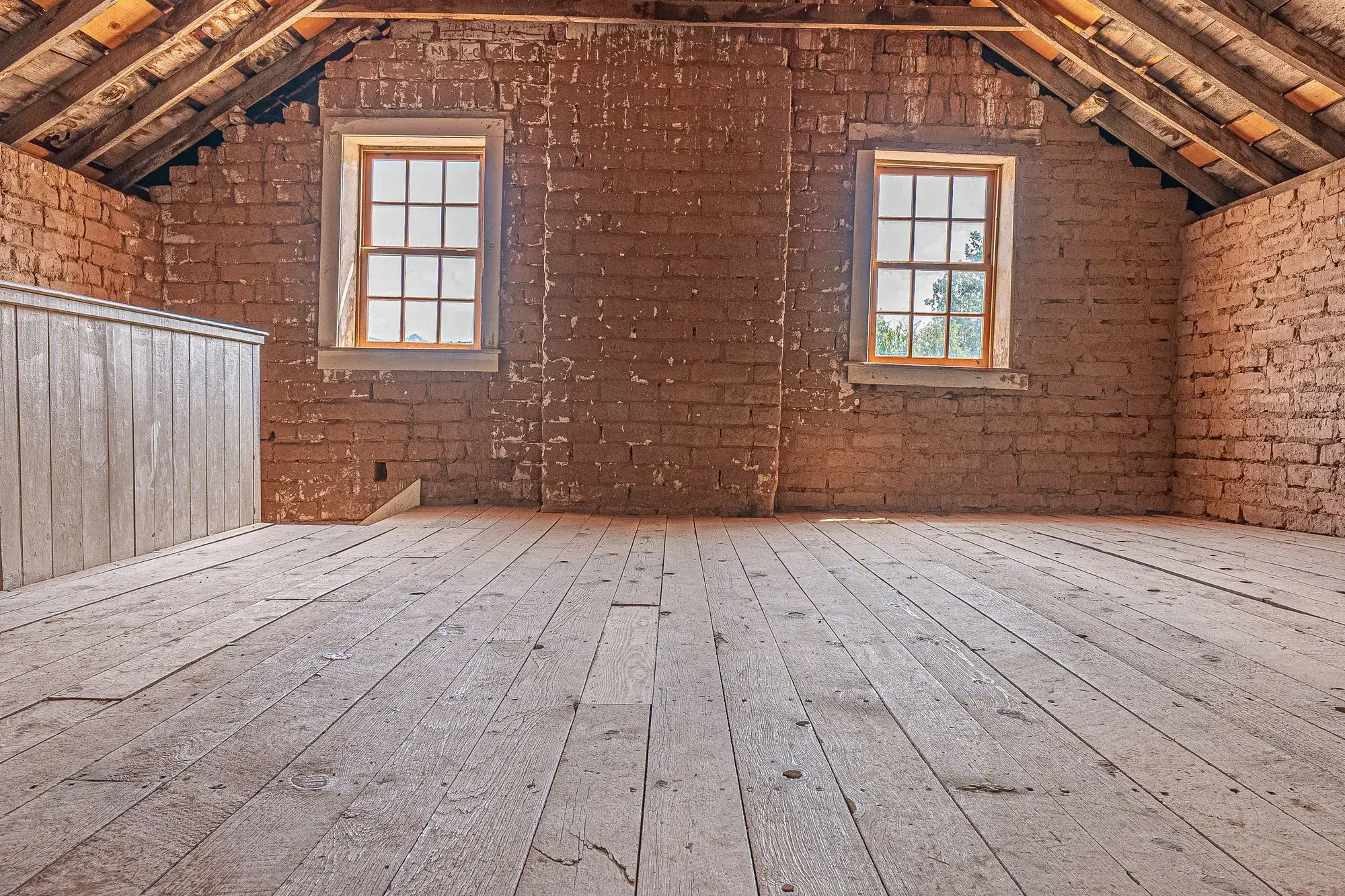 Empty attic with exposed rafters and a wooden floor