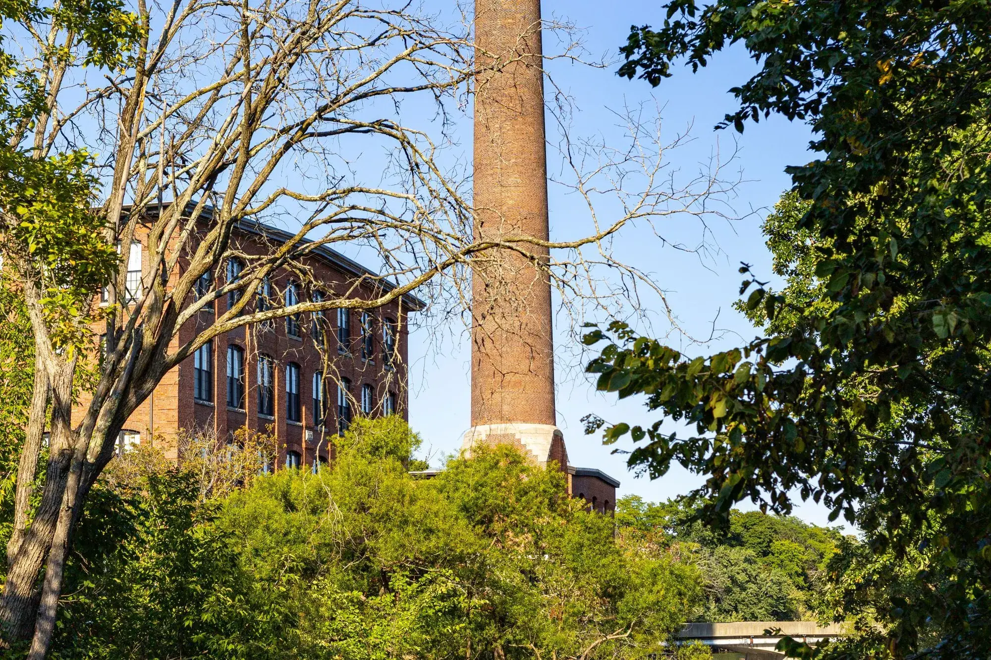 Brick mill building and a tall chimney beside a river