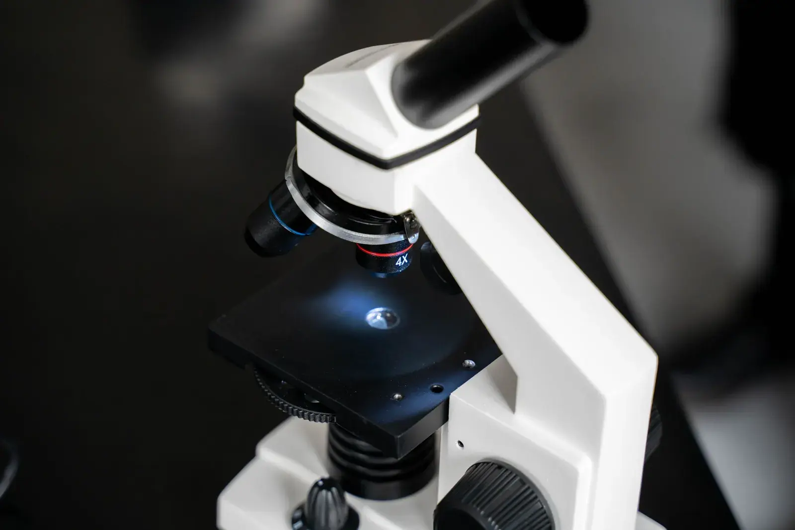 White laboratory microscope with a slide on the stage